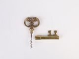 a bottle opener and a corkscrew on a white surface