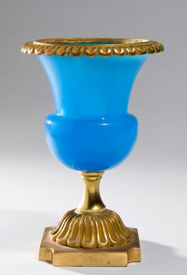 a blue vase on a gold stand on a white background