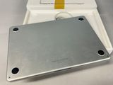 an open box with a silver tablet computer sitting on top of a white table