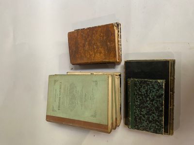 trois vieux livres posés sur une surface blanche, dont l'un n'a plus de couverture