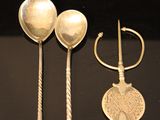 three silver spoons and two silver spoons on a black surface