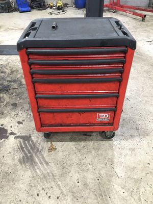 une boîte à outils rouge et noire posée sur un sol en béton