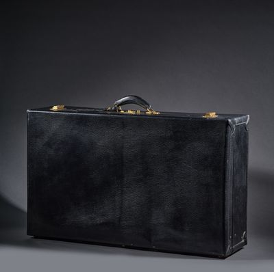 une valise noire posée sur une table près d'un mur