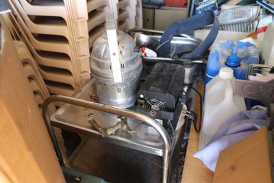 un chariot métallique sur lequel est posé un mixeur, dans une pièce encombrée