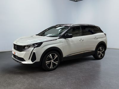 Une voiture blanche est garée dans une grande pièce équipée d'un ventilateur de plafond.