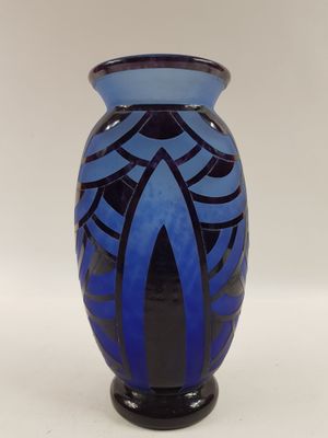 un vase bleu et noir posé sur une surface blanche