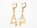une paire de boucles d'oreilles en or ornées de perles sur fond blanc