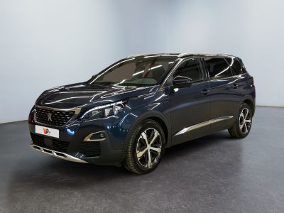Une voiture bleue est garée dans une pièce aux murs blancs.