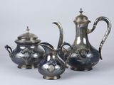 two silver teapots and a sugar bowl on a table