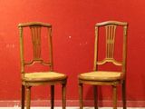 une paire de chaises en bois adossées à un mur rouge dans une pièce