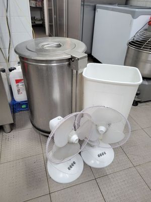 un ventilateur posé par terre à côté d'une poubelle