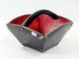 un petit bol noir et rouge posé sur une surface blanche