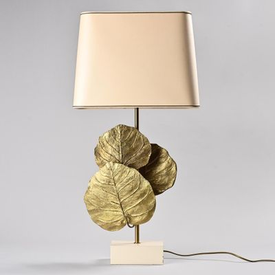 gold leaf table lamp with a beige shade on a white base