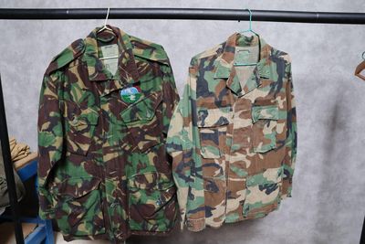 deux vestes militaires suspendues à un porte-manteau dans une pièce