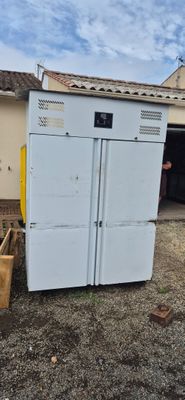 a white refrigerator sitting outside of a building next to a building