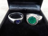 pair of emerald and sapphire rings in a black box on a table