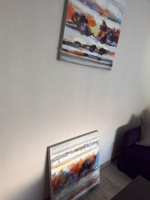a picture of a living room with a couch and a painting on the wall