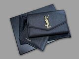 un gros plan d'un portefeuille noir orné d'un logo YSL doré