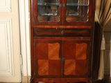 a wooden cabinet with glass doors in the corner of a room