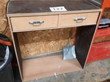a wooden desk with drawers and a trash can in the corner
