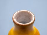 a yellow vase sitting on a table with a blue background