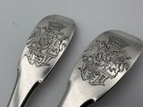 two silver spoons with a coat of arms on them