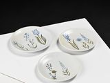 three plates with flowers painted on them sitting on a piece of paper
