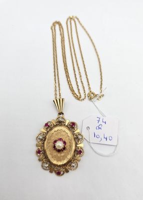 un collier en or orné d'une pierre rouge et blanche au centre