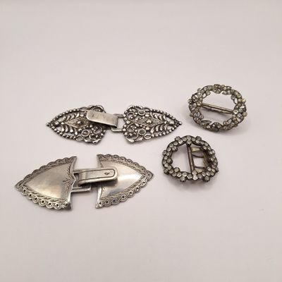 un ensemble de broches et de boucles en métal argenté sur un fond blanc