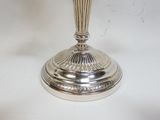 un vase argenté posé sur une table blanche, sur fond blanc