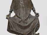 statue en bronze représentant un homme assis sur une chaise, les mains posées sur ses genoux