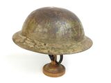 an old helmet is sitting on a wooden stand on a white surface