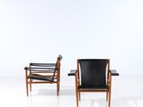 two black leather chairs in a white room with a white wall