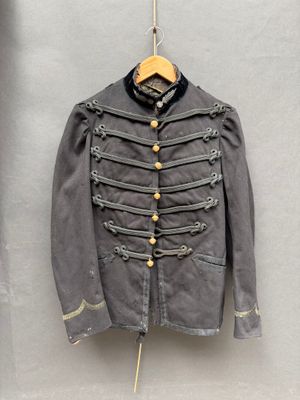 une vieille veste militaire accrochée au mur à côté d'un cintre en bois