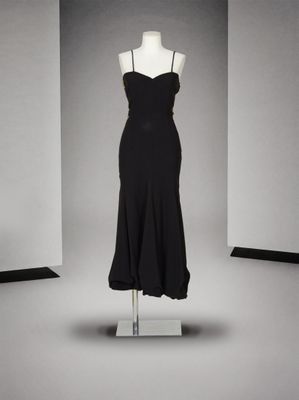 une robe noire posée sur un mannequin devant un mur blanc