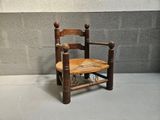 a small wooden chair with a rope on the back of it