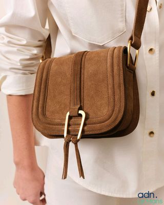 une femme portant une chemise blanche et un sac à main marron