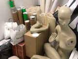 a mannequin sitting on a chair next to a pile of boxes