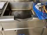 un évier en inox dans une cuisine où se trouve un panier rempli d'ustensiles