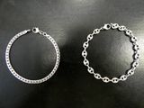 deux bracelets en argent posés sur une surface noire, sur fond noir