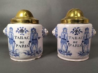 Deux bocaux bleus et blancs aux couvercles dorés sont posés sur une table