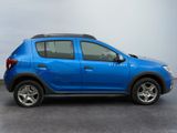 the small blue car is parked in a parking lot on a cloudy day