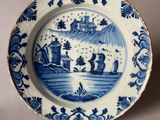 une vieille assiette bleue et blanche sur laquelle est représenté un château