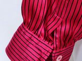 pink and black striped shirt hanging on a hanger against a white wall