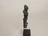 a bronze statue of a woman holding a basket on top of a wooden block