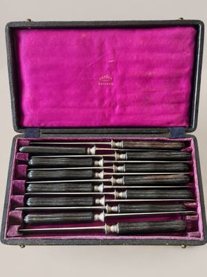 an old set of six knives in a case on a table