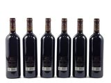 six bottles of wine are lined up in a row on a white surface