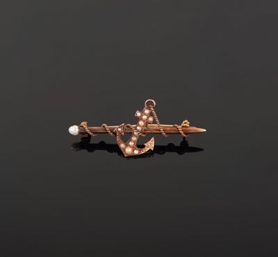 a gold anchor and pearl broochle on a black background