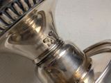 a silver tea pot with a handle on a table