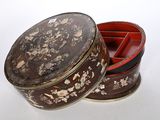 a small round box with a lid that has flowers and birds on it